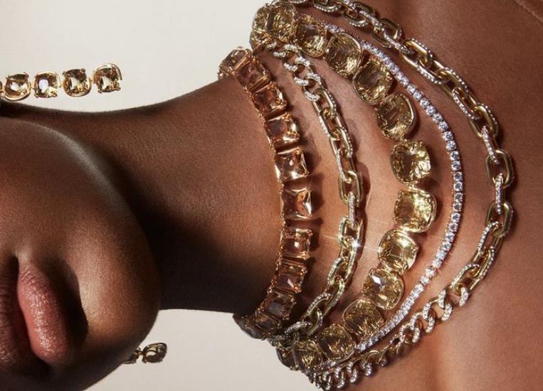 Model wearing layered gold and gemstone collar necklaces