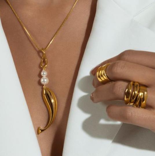 Gold pendant necklace resting on white fabric